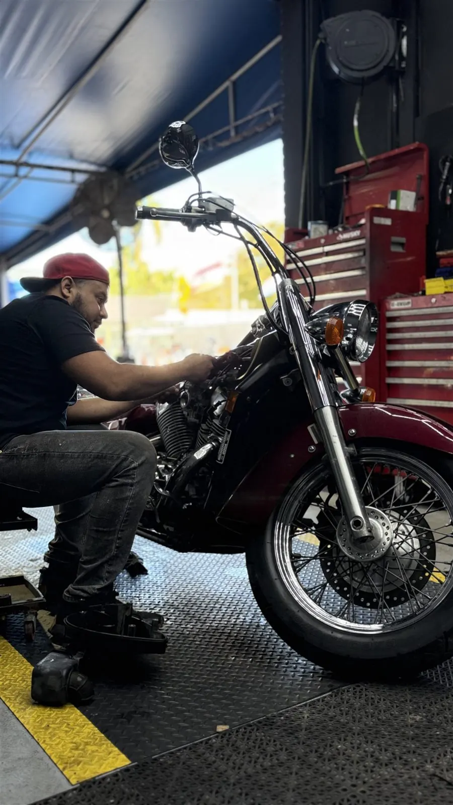 Technician diagnosing a motorcycle inside the Pulgar Motors shop in Miami.