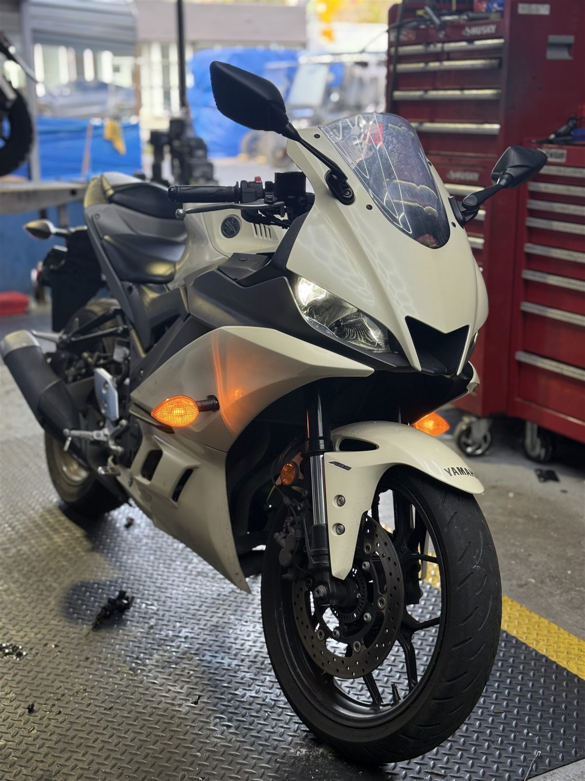 White motorcycle being serviced inside the Pulgar Motors workshop.